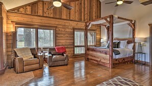 A log cabin interior with a four-poster bed, leather recliner, and a ceiling fan. - Hot Tub, Grill: Hilltop Log Cabin in Hot Springs! (Hot Springs)