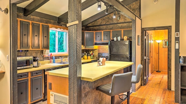 A kitchen with dark wooden cabinets, a large island, and a stone backsplash. - 'stonewood Lodge' Couples Retreat in Glenville! (Glenville)