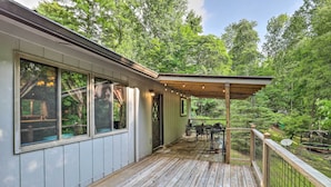 A covered deck with a table and chairs, surrounded by a wooden railing and a view of a lush green forest. - 'stonewood Lodge' Couples Retreat in Glenville! (Glenville)