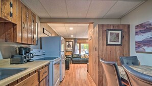 A compact RV kitchen with wooden cabinets, a refrigerator, a coffee maker, and a dining area with a table and chairs. - 'james West' Apt w/ 50 Acres Near Raystown Lake (Huntingdon)