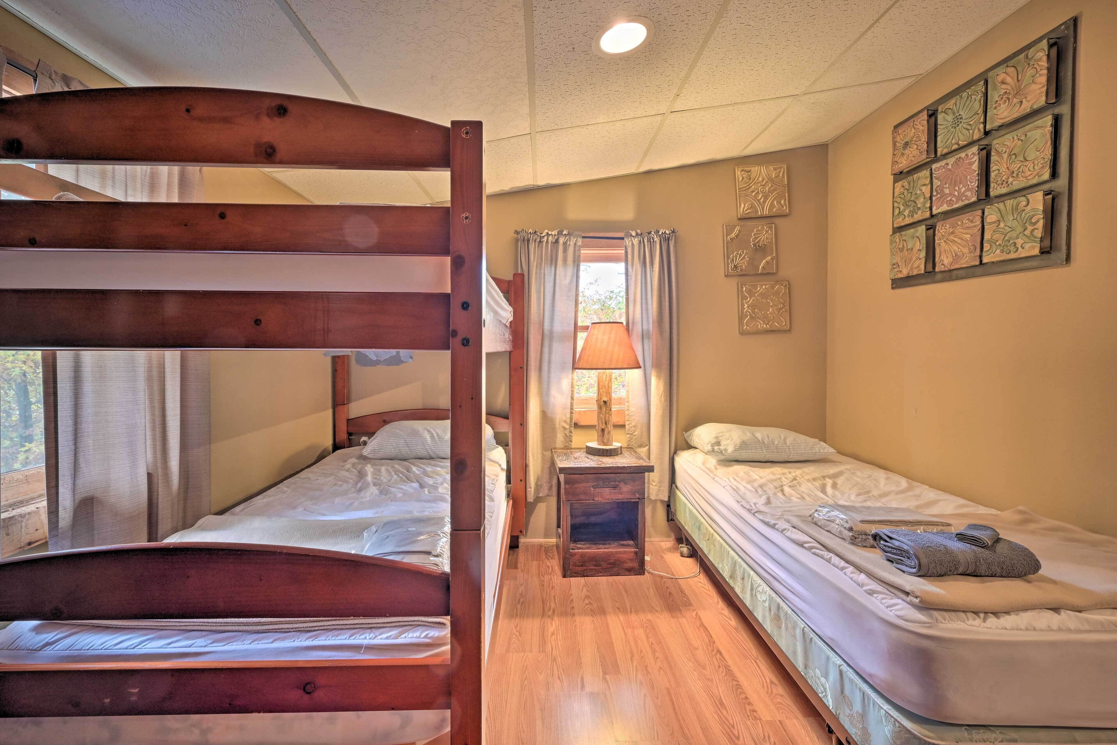 Una habitación con literas, una cama individual, una mesita de noche con lámpara y una pared con azulejos decorativos.