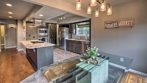 A modern kitchen with a central island, stainless steel appliances, and a farmhouse-style sign. - Waterfront Beaver Lake Hideaway w/ Kayaks & More! (Springdale)