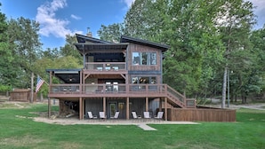 A two-story wooden house with a balcony, a deck, and a flag. - Waterfront Beaver Lake Hideaway w/ Kayaks & More! (Springdale)