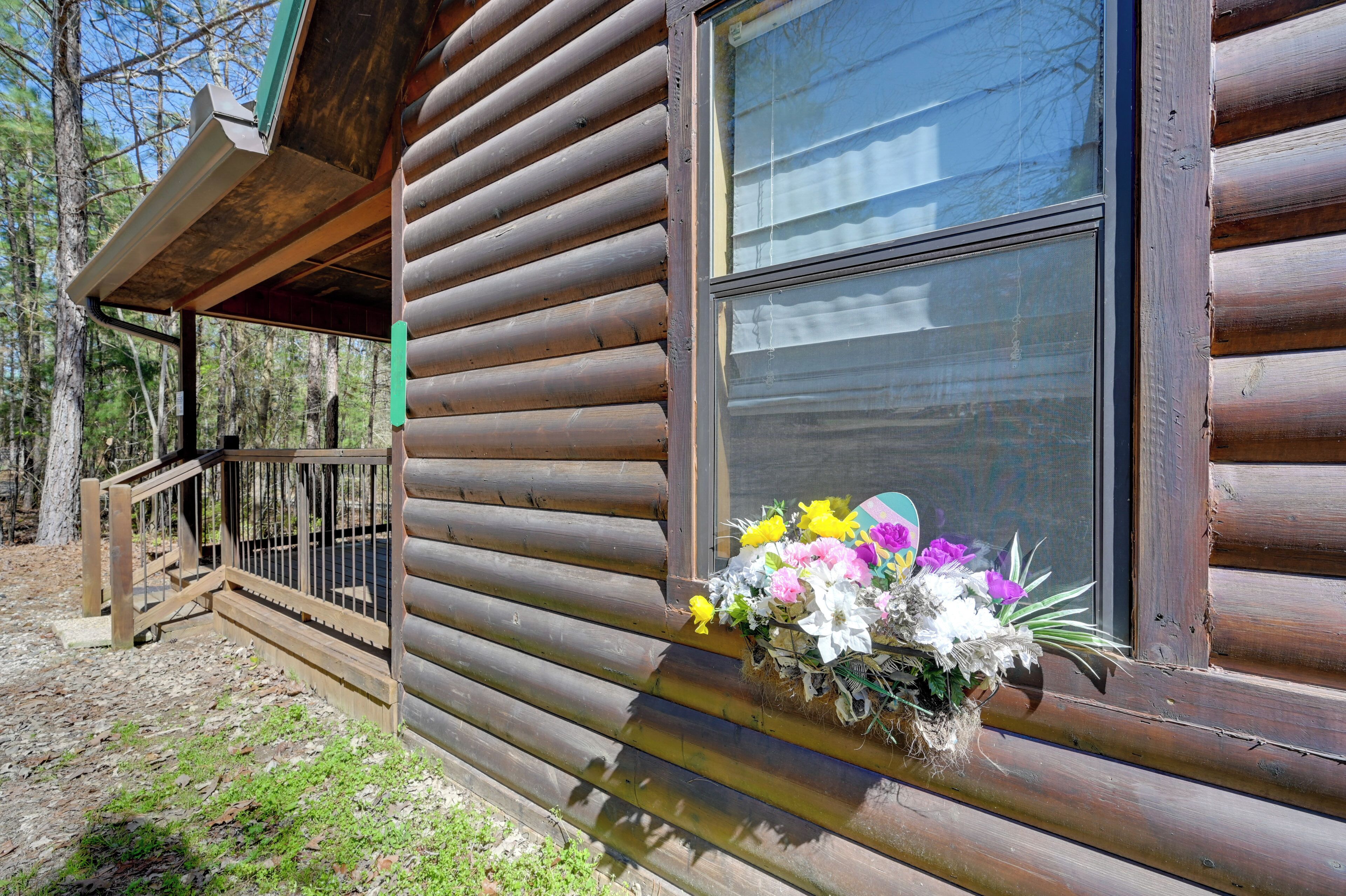 Una cabaña de troncos con una ventana decorada con un arreglo floral.