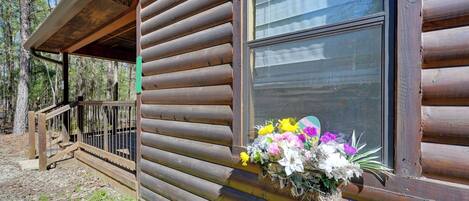 Una cabaña de troncos con una ventana decorada con un arreglo floral.