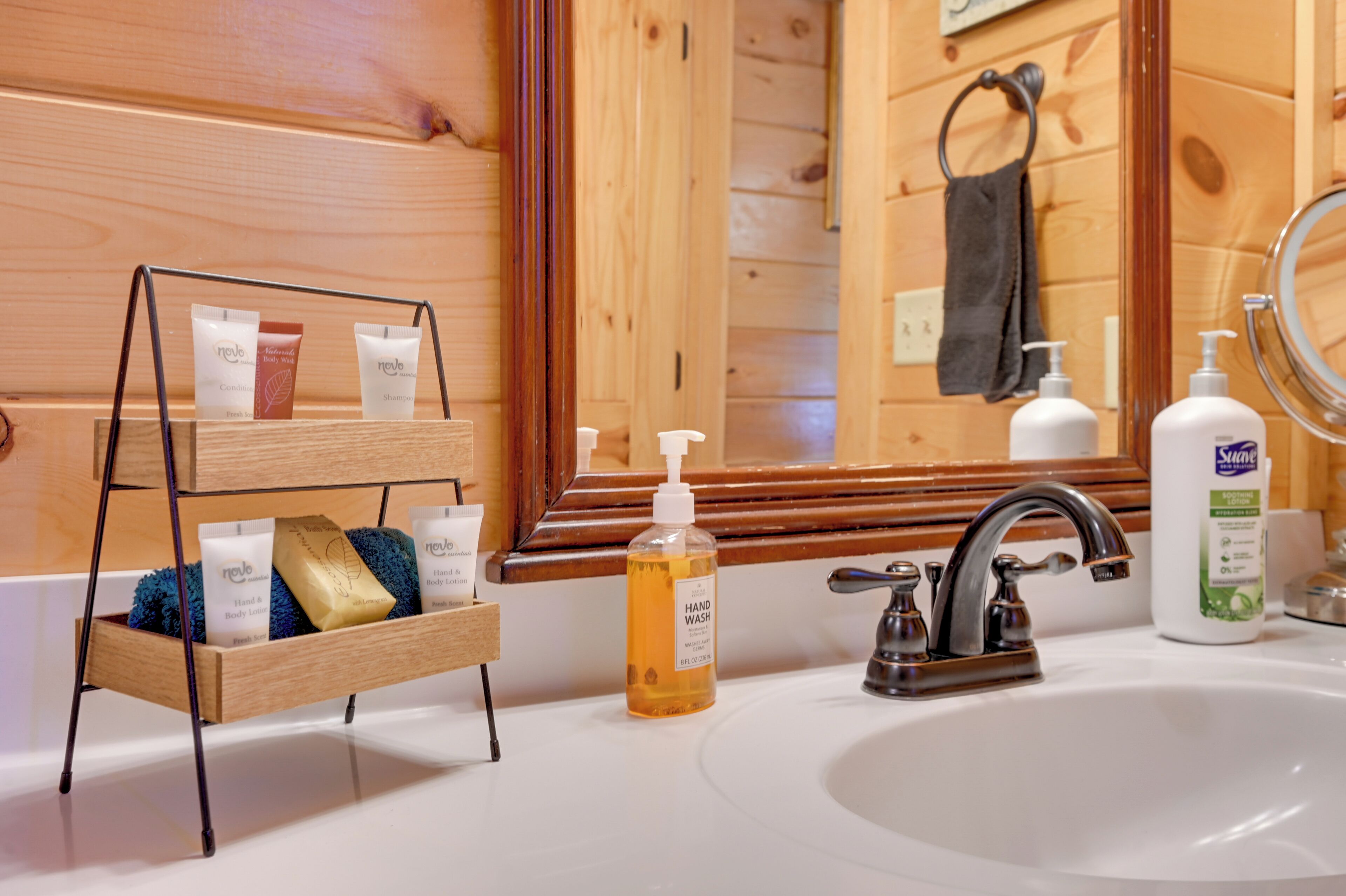 A wooden cabin bathroom with a wooden shelf holding toiletries, a sink with a faucet, and a mirror.