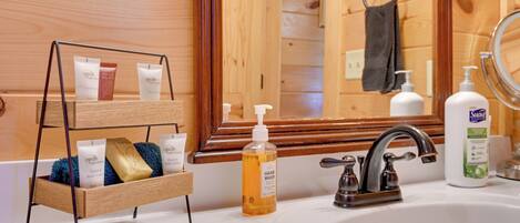 A wooden cabin bathroom with a wooden shelf holding toiletries, a sink with a faucet, and a mirror.