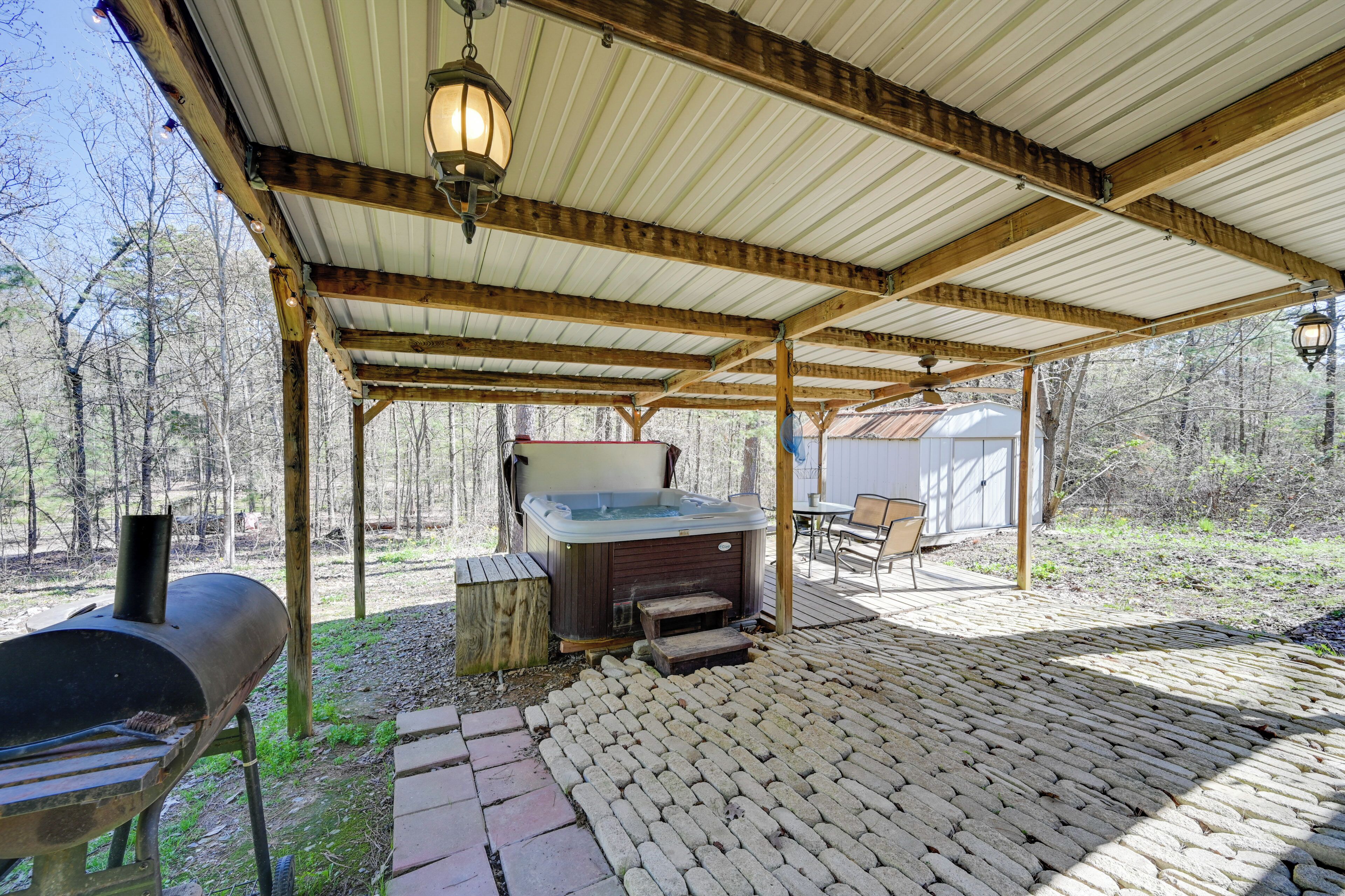 A covered outdoor area with a hot tub, a grill, and a wooden deck.