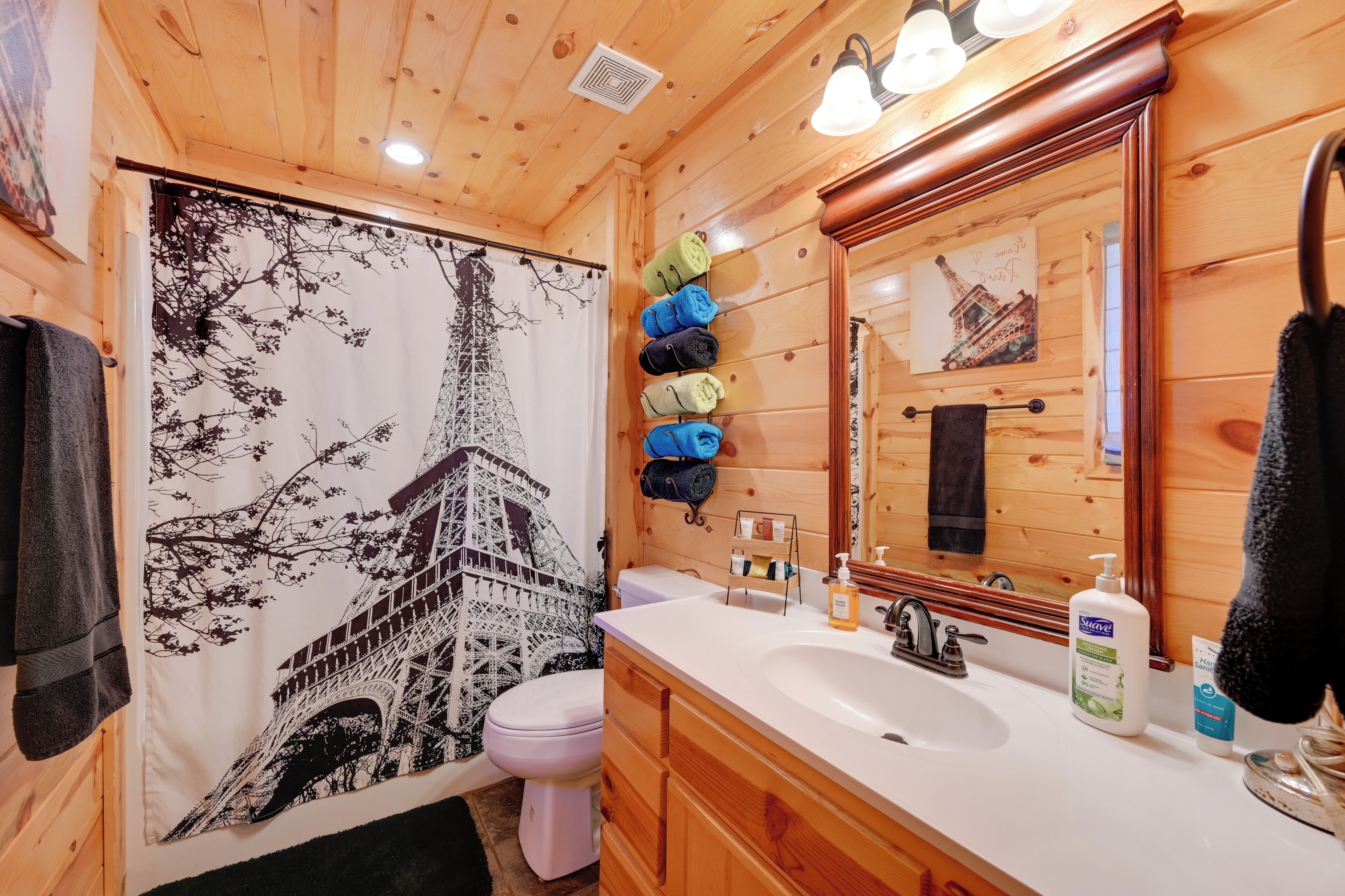 Un baño de cabaña de madera con un espejo grande, un lavabo y un inodoro.