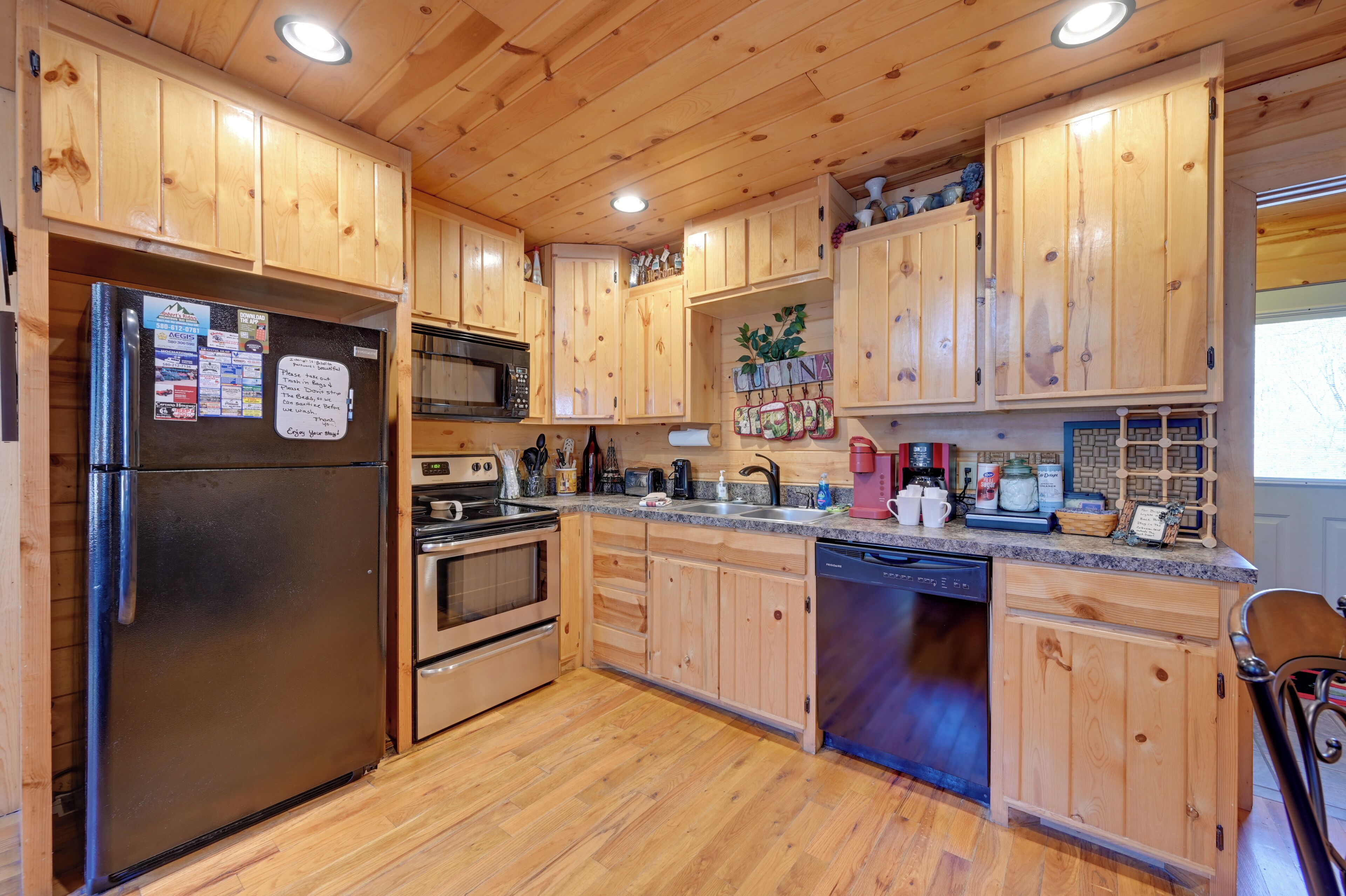 A kitchen with wooden cabinets, a refrigerator, a microwave, an oven, and a dishwasher.