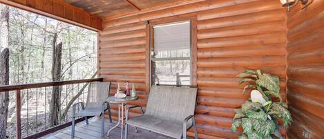 A wooden cabin with a porch, a bench, a table, and a potted plant.
