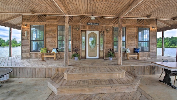 A wooden cabin with a covered porch, a central door with glass panels, and a bench on the left. - Secluded Angler's Haven - Boat + Fish! (Rosston)