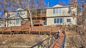 Ein zweistöckiges Haus mit einer Holzterrasse und einer Metalltreppe, die zu einem Balkon im zweiten Stock führt.