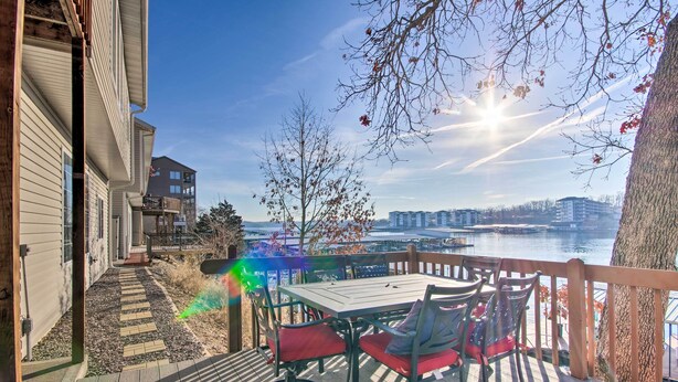Eine Terrasse mit Tisch und Stühlen mit Blick auf einen Fluss und Gebäude.