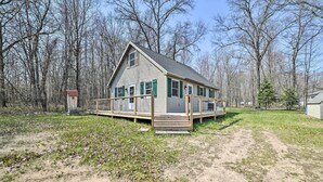 Een gelijkvloers huis met een houten terras, omgeven door een gazon en kale bomen.