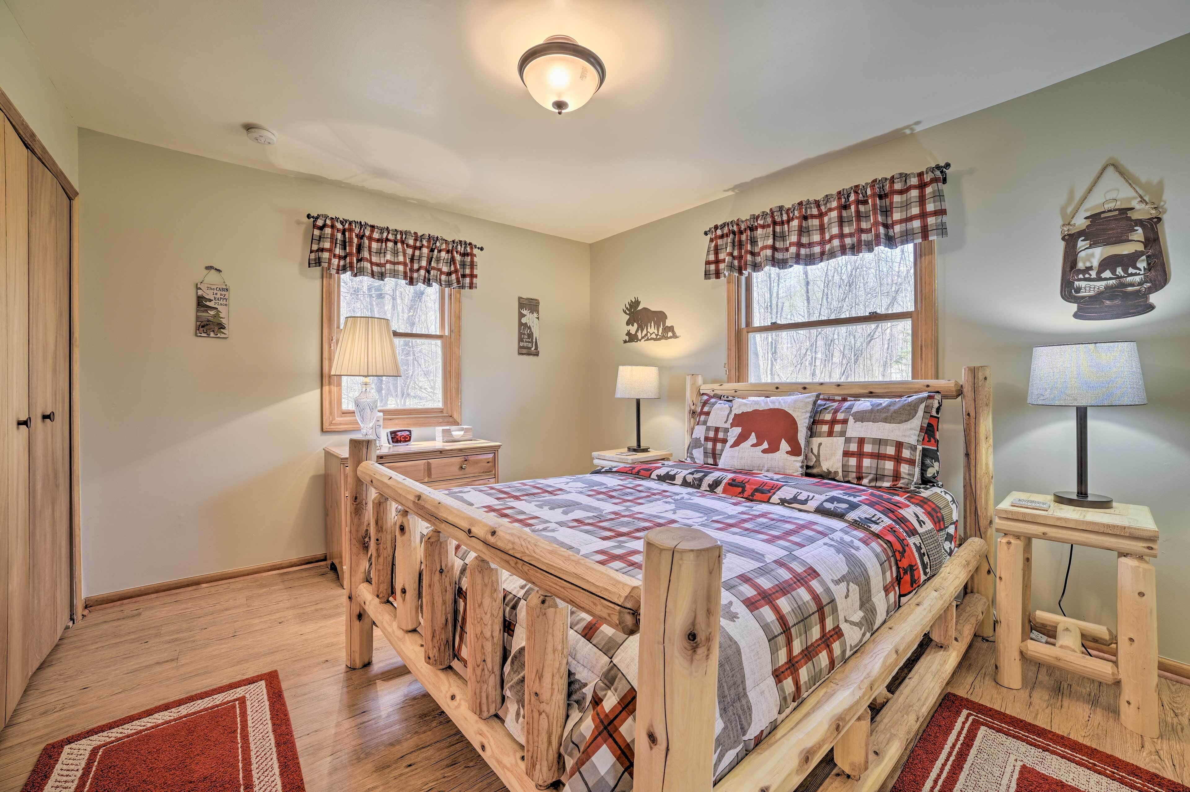 A cozy bedroom with a wooden bed frame, plaid bedding, and a small bedside table with a lamp.