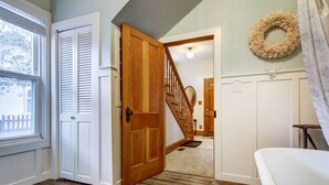 A hallway with a wooden door, a staircase, and a wall-mounted wreath. - Monument Retreat - Walk to Local Dining & Shopping (Monument)