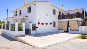 A two-story white building with a balcony, a covered entrance, and potted plants. - Cozy Apartment El Pajar near El Chorro (El chorro)