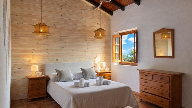 A bedroom with a wooden ceiling, a bed with white linens, two bedside lamps, a wooden dresser, and a window with a view. - Cozy Apartment El Pajar near El Chorro (El chorro)