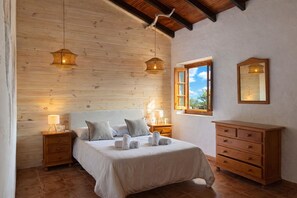 A bedroom with a wooden ceiling, a bed with white linens, two bedside lamps, a wooden dresser, and a window with a view. - Cozy Apartment El Pajar near El Chorro (El chorro)