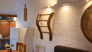 A kitchen with a wooden ladder, a dining table with chairs, a refrigerator, and a woven basket on the wall. - Cozy Apartment El Pajar near El Chorro (El chorro)