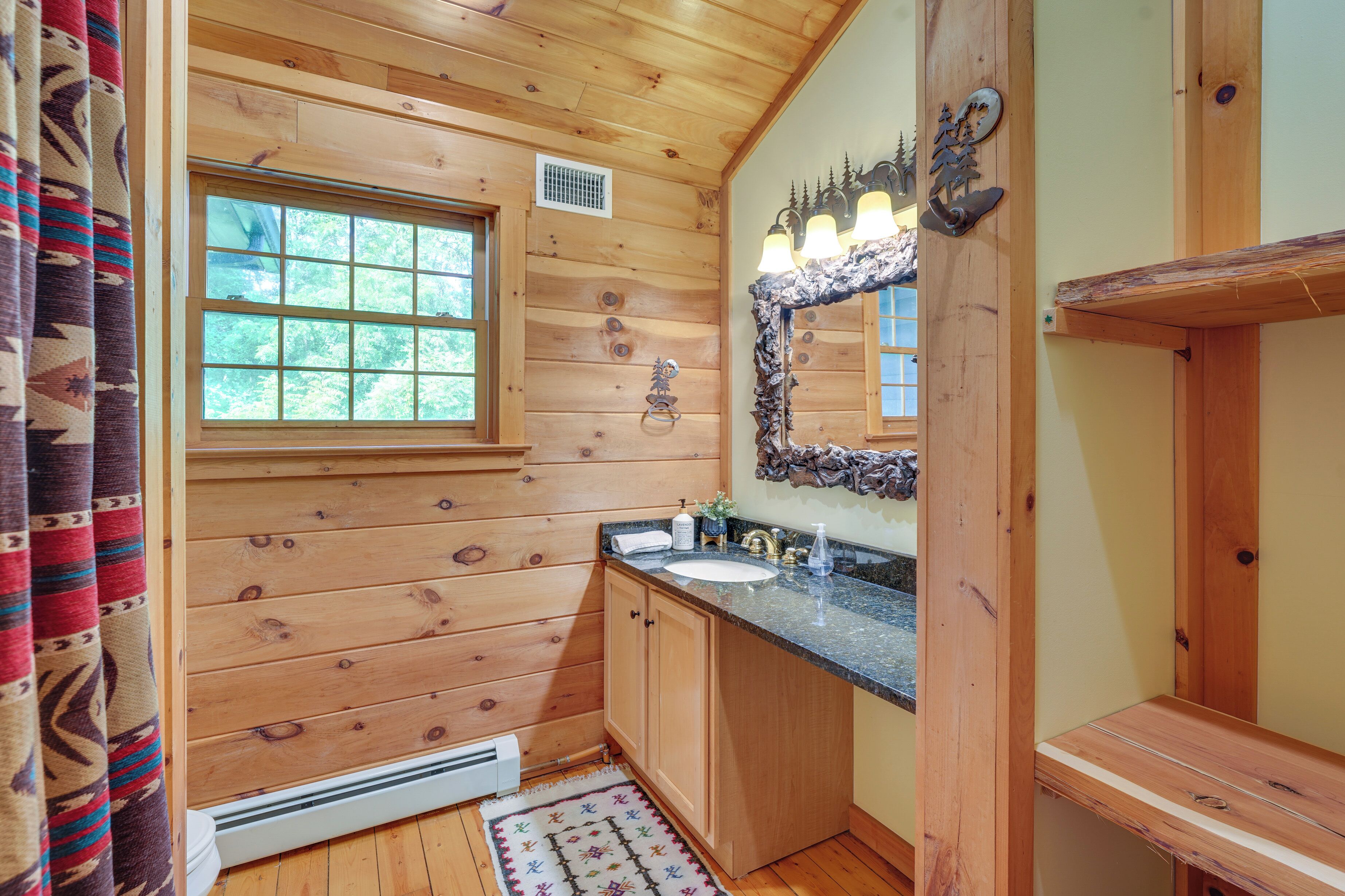 Une salle de bain rustique, avec des murs en bois, une fenêtre, un lavabo et un miroir.