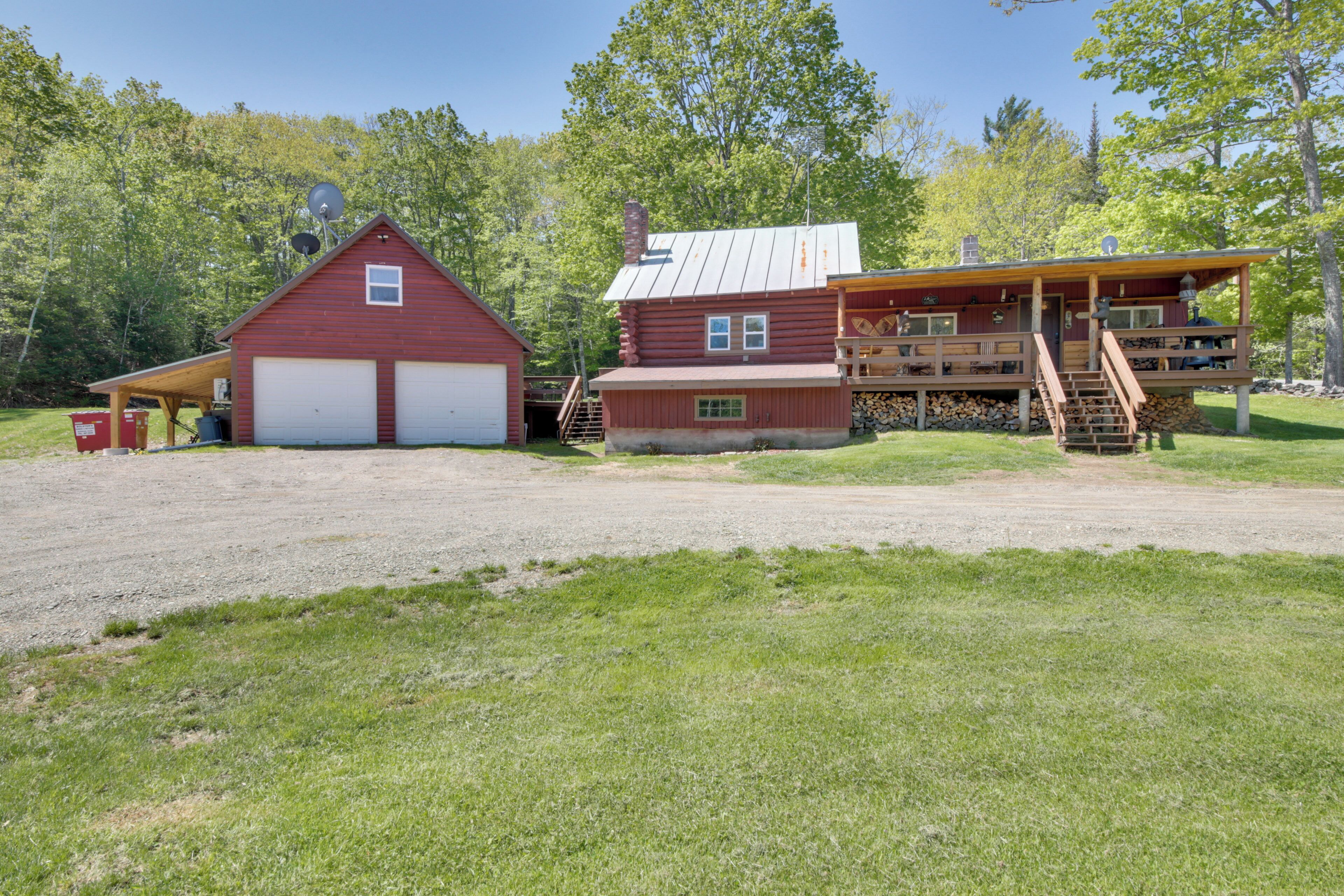A red barn with two garage doors, a wooden deck, and a staircase leading to a second-story level.