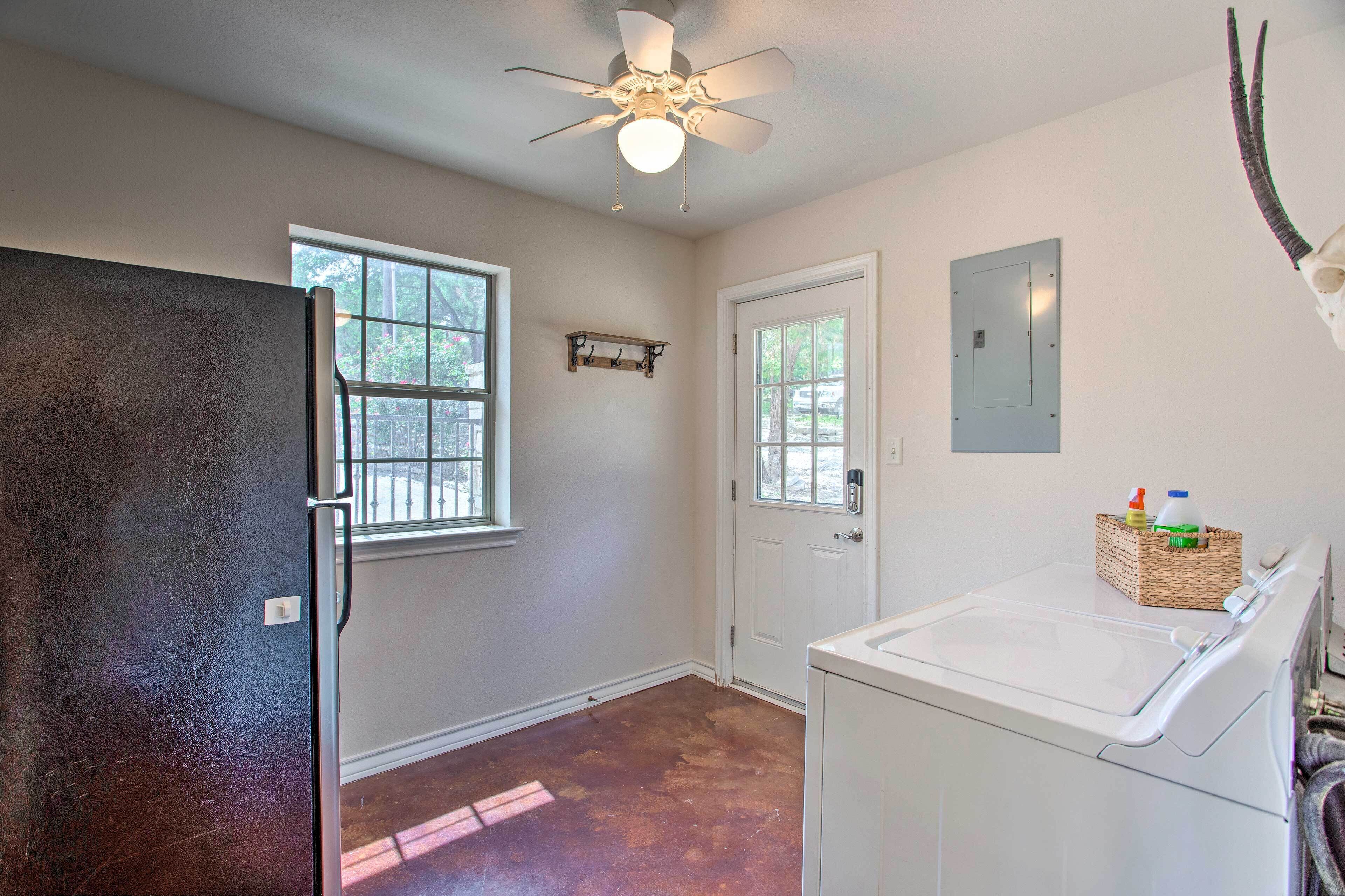 A laundry room with a washing machine, a ceiling fan, and a door with a window.