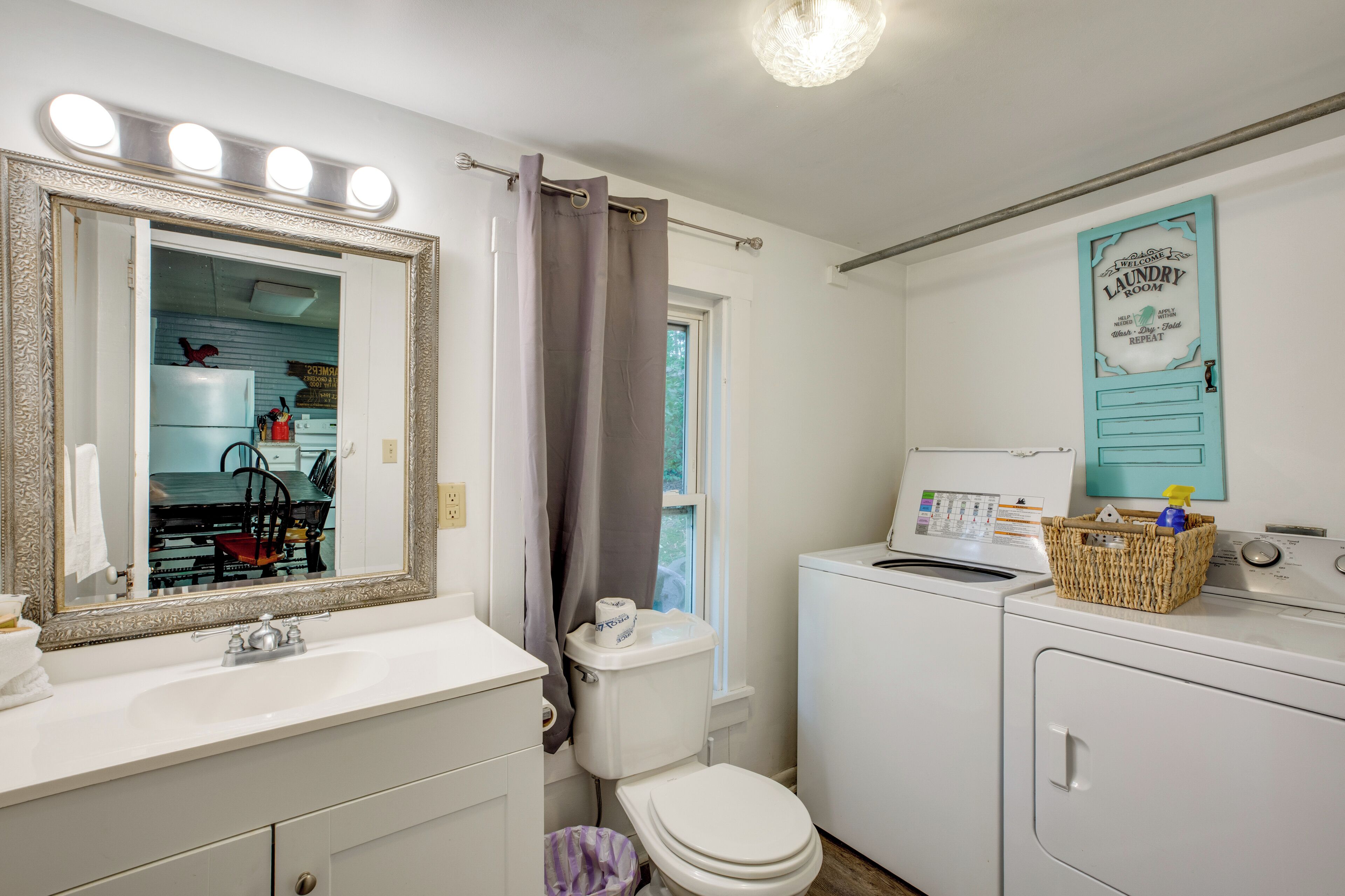 A bathroom with a mirror, sink, toilet, and a washing machine.