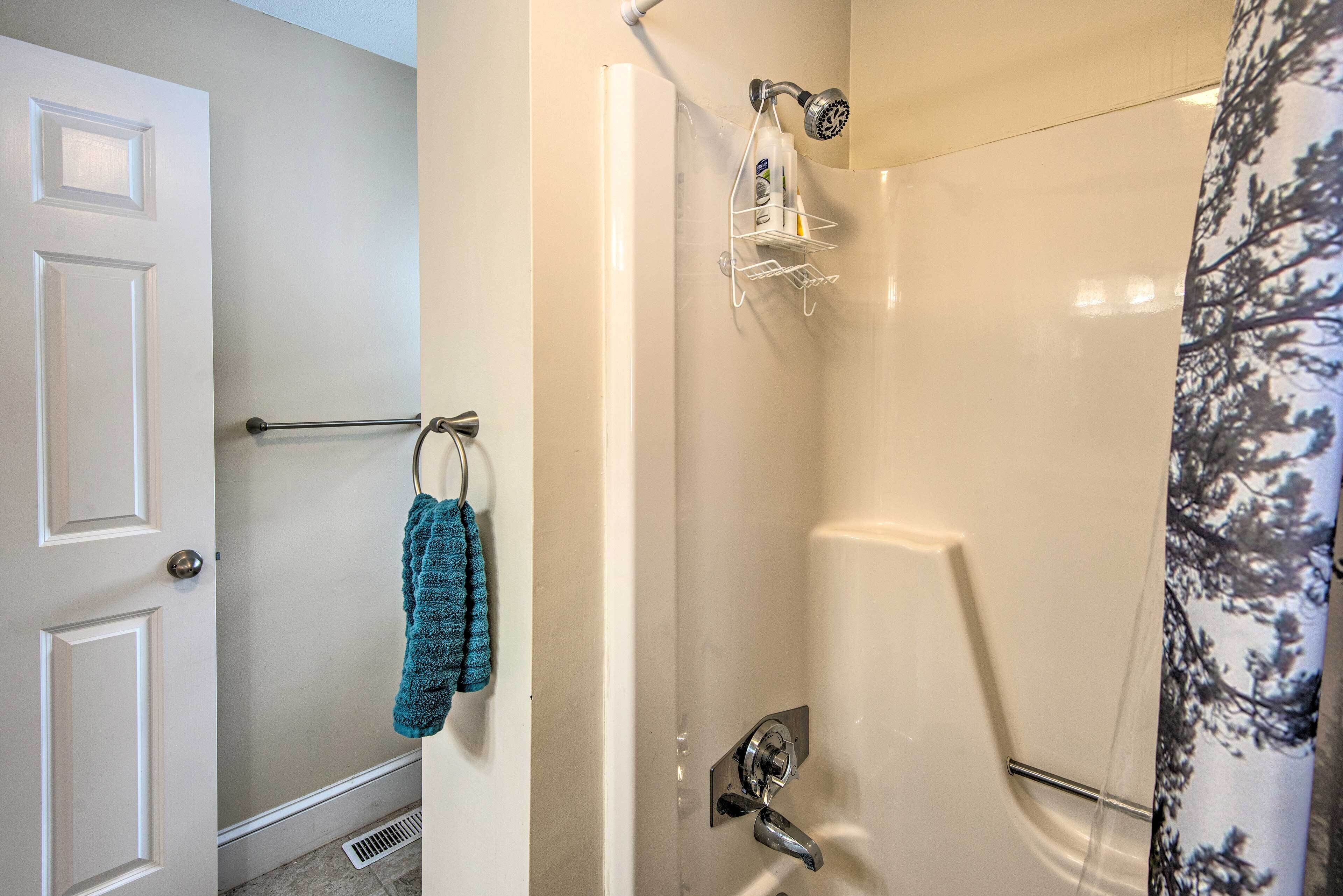 Een badkamer met een douche, een handdoekrek met een blauwe handdoek en een deur met een deurklink.