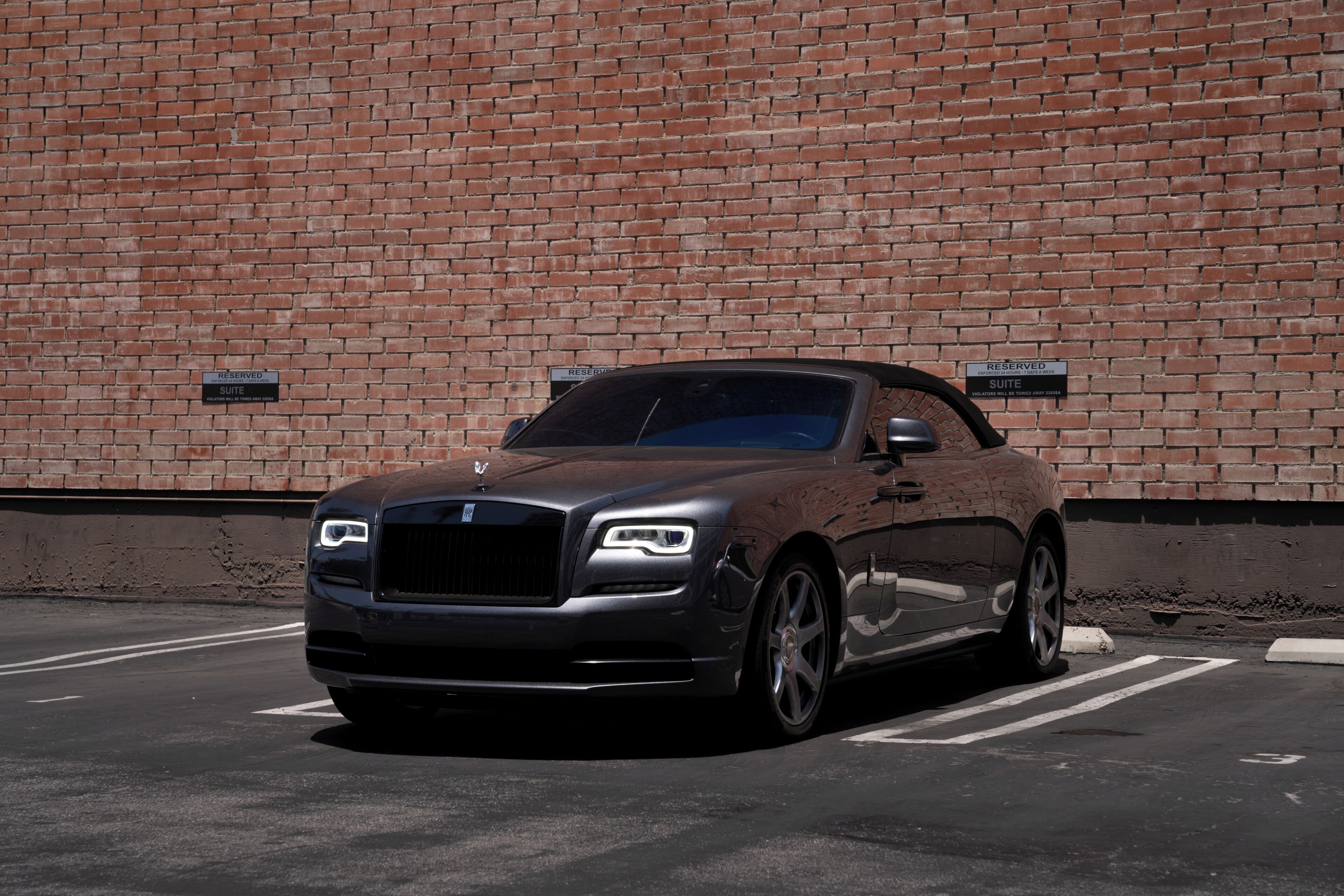 A luxury car parked in a parking lot with a brick wall in the background.
