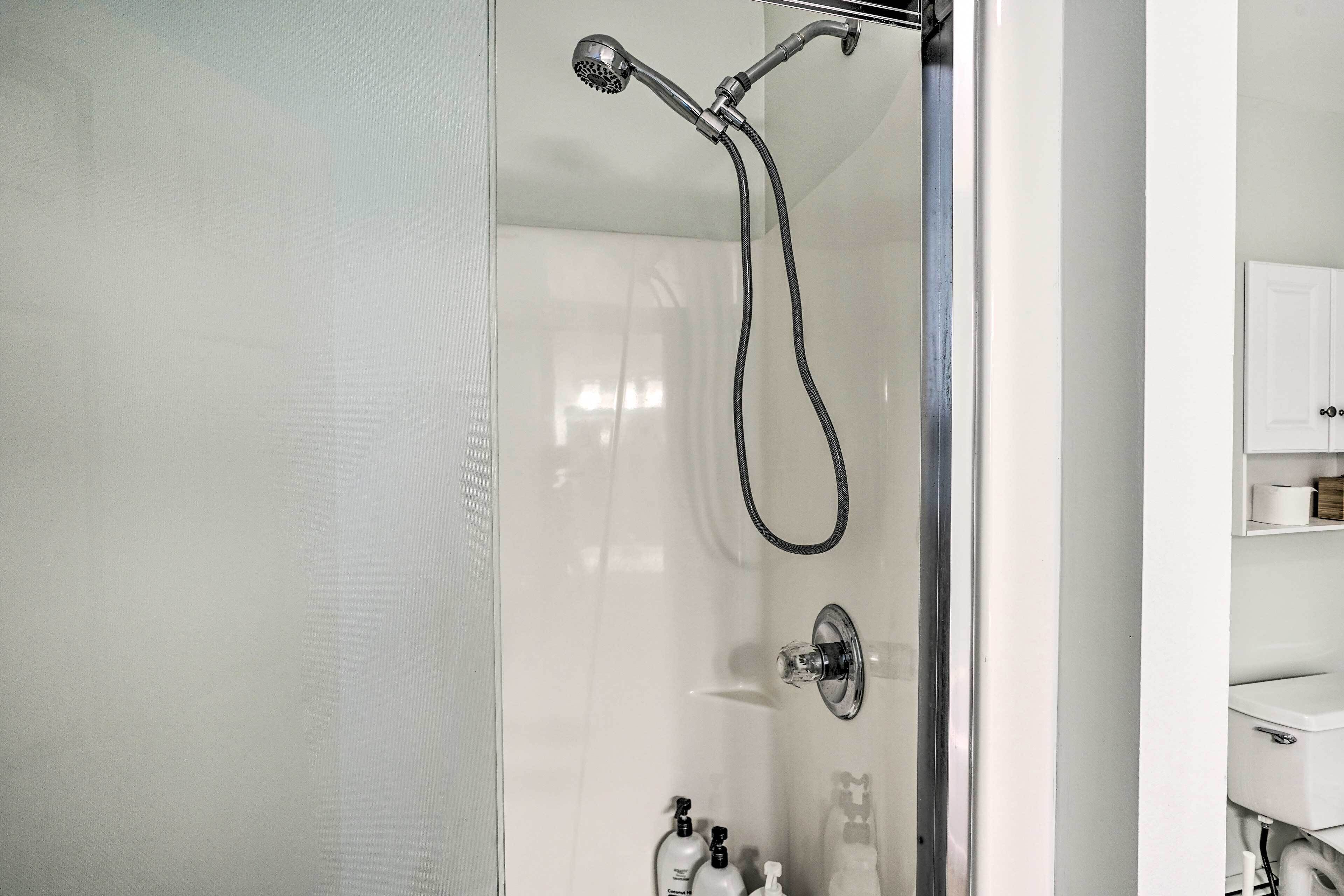 A modern bathroom with a glass-enclosed shower, a toilet, and a sink.