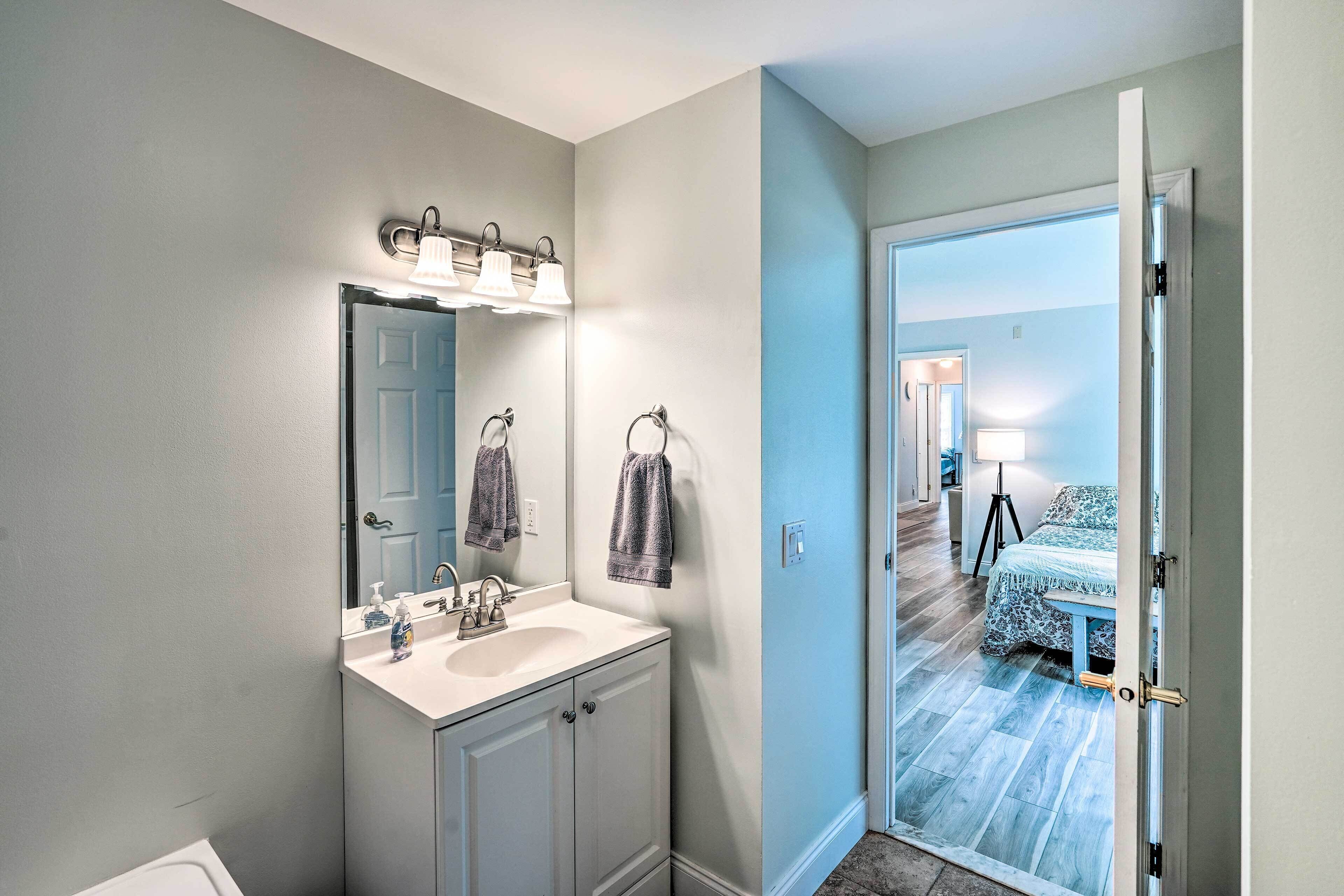 A bathroom with a sink, mirror, and towel rack.