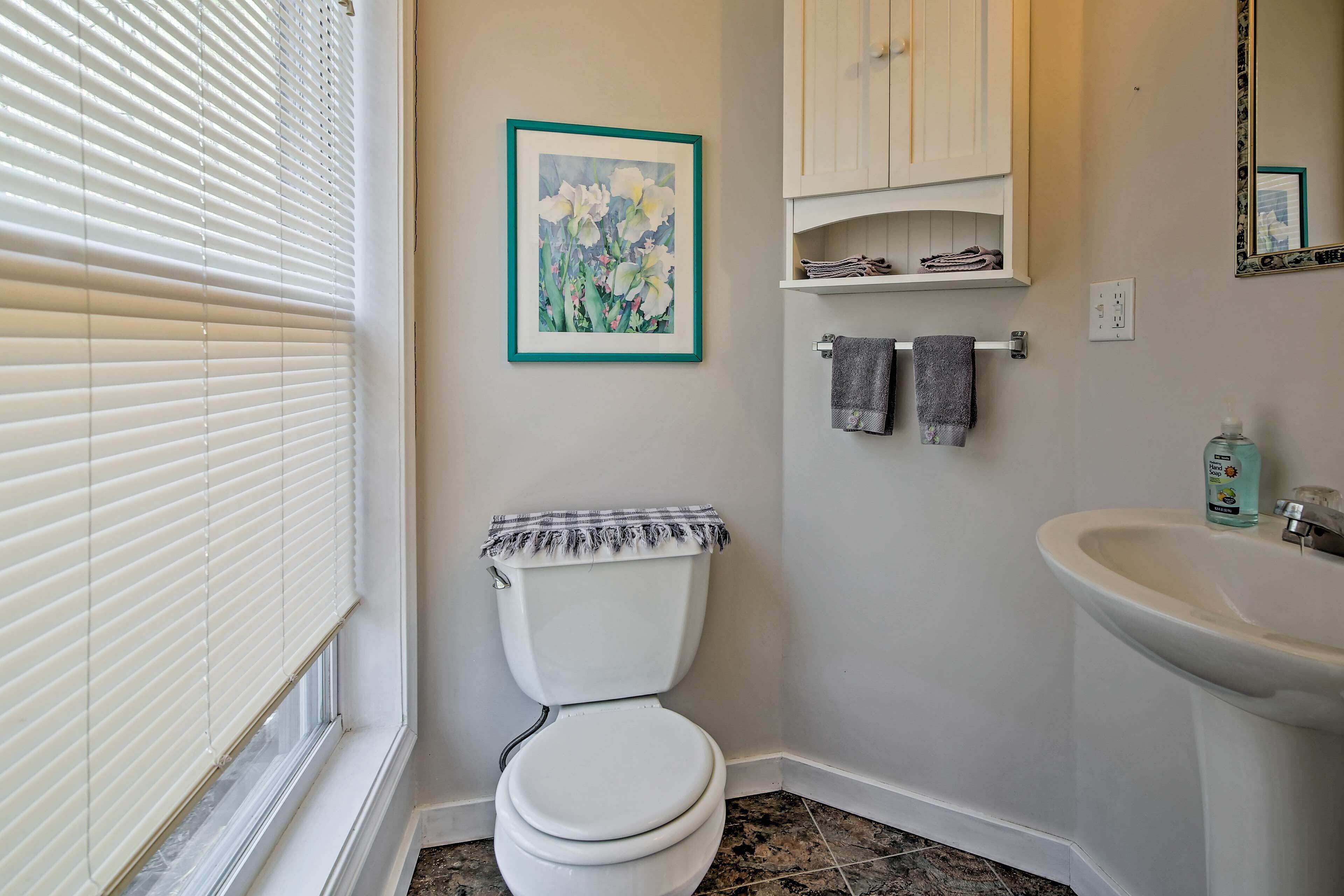A bathroom with a toilet, sink, and a framed picture on the wall.