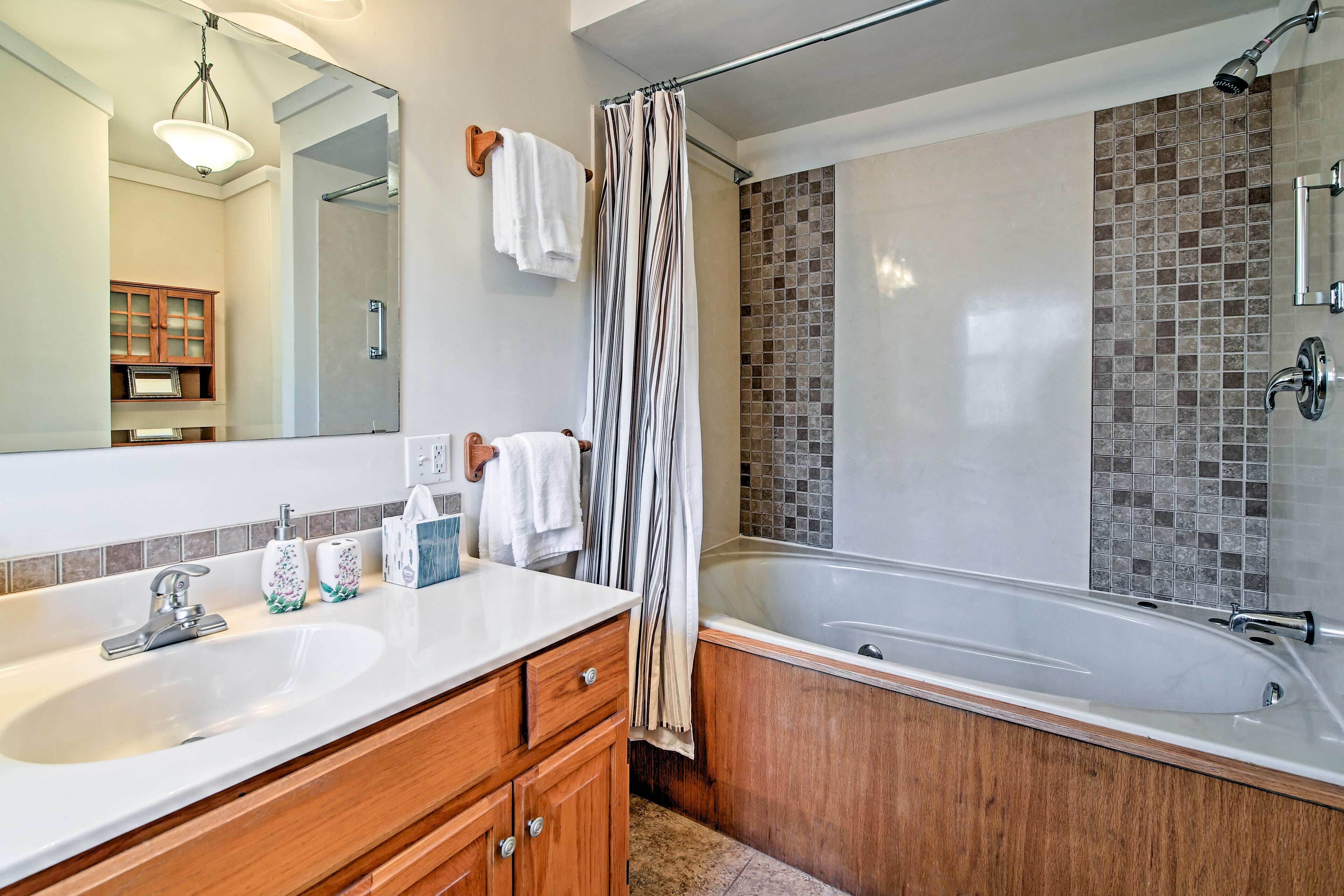 A modern bathroom with two sinks, a bathtub, and a shower.