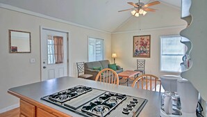 A kitchen with a gas stove, a coffee maker, a ceiling fan, and a dining area with a table and chairs.