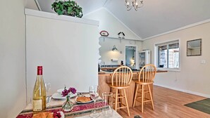 A dining area with a table set for two, a bottle of wine, and a plate of food.