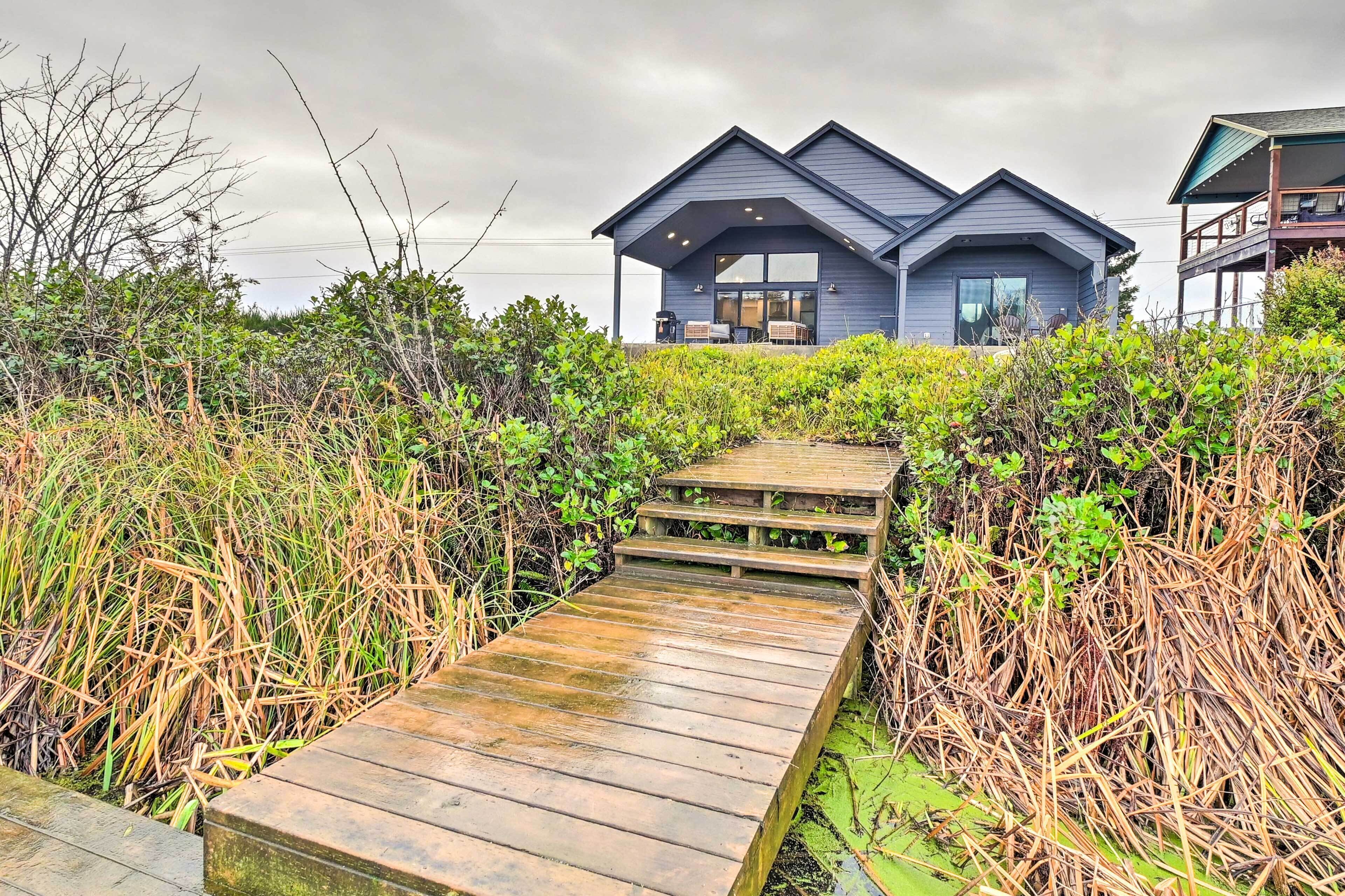 Uma casa moderna com varanda coberta e deck de madeira que dá acesso à entrada.