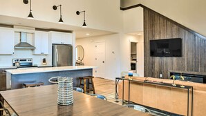 A modern kitchen with white cabinets, stainless steel appliances, and a wooden dining table.