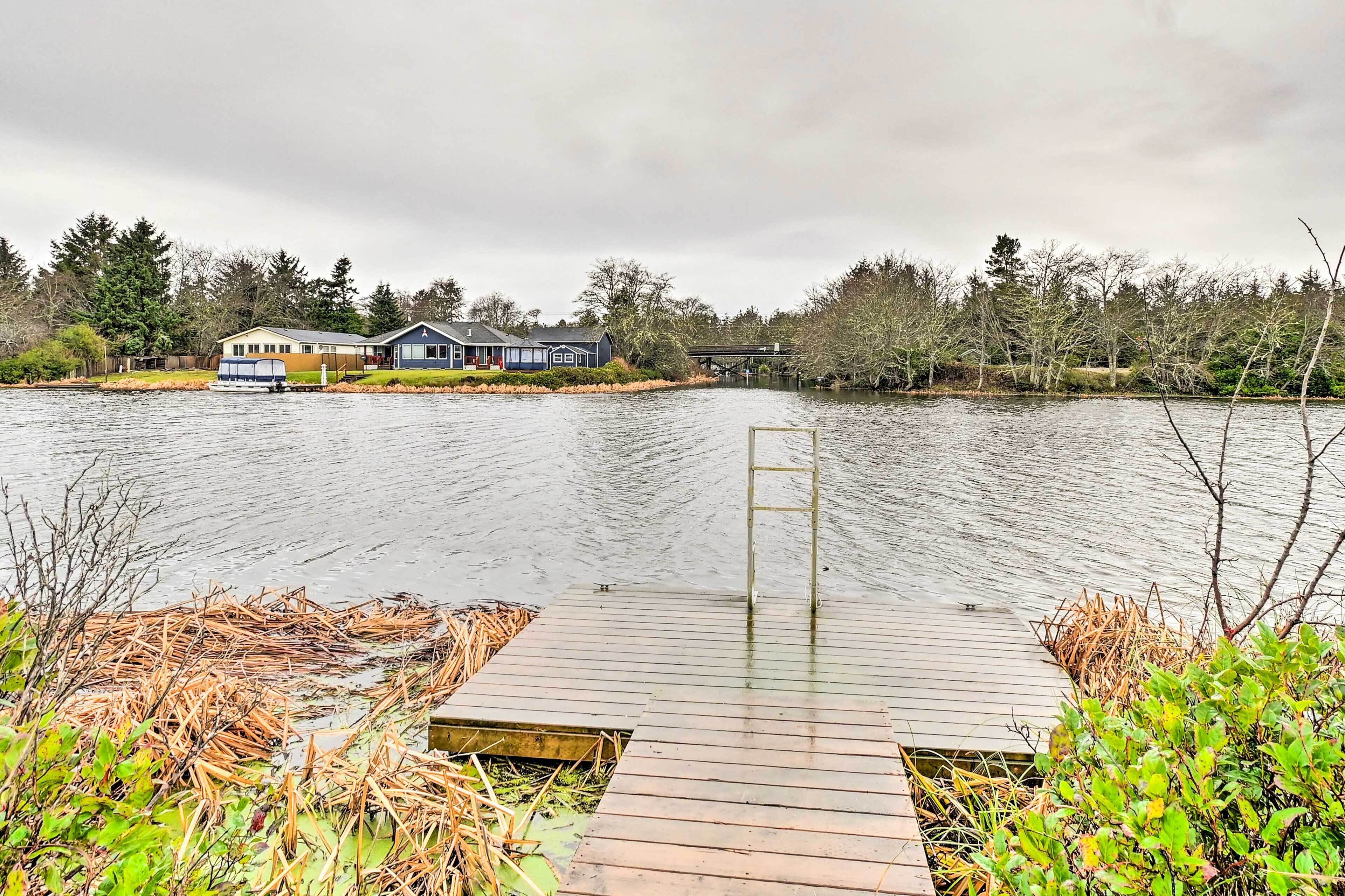 A wooden dock extending into a calm lake with a house in the background.