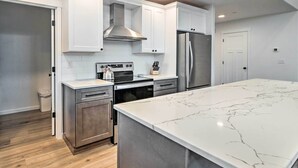 A modern kitchen with white cabinets, stainless steel appliances, and a large marble island.