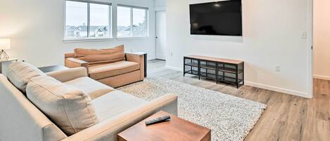 Un salon moderne avec un canapé, une table basse et un téléviseur fixé au mur.