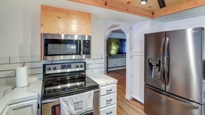 Une cuisine moderne dotée d’appareils électroménagers en acier inoxydable, de poutres en bois au plafond et de meubles blancs.