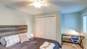 A bedroom with a bed, a desk, a chair, a ceiling fan, and a closet.