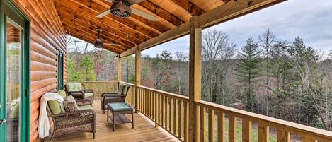 A wooden deck with wicker furniture and a ceiling fan.