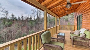 A wooden deck with wicker furniture and a ceiling fan. - Cozy Mtn Cabin: Spacious Deck & Forest Views! (Murphy)