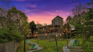 A house with a backyard containing mini-golf holes and a wooden deck. - Hot Tub & Mini Golf: Mtn-view Haven in Kodak! (Kodak)