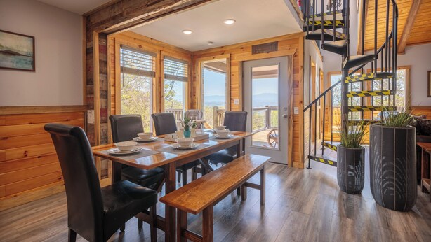 A wooden dining area with a bench, chairs, and a table set for four. - Hot Tub & Mini Golf: Mtn-view Haven in Kodak! (Kodak)