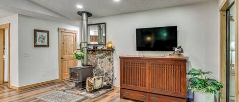 Una sala de estar con pared de piedra, chimenea, aparador de madera y televisor de pantalla plana.