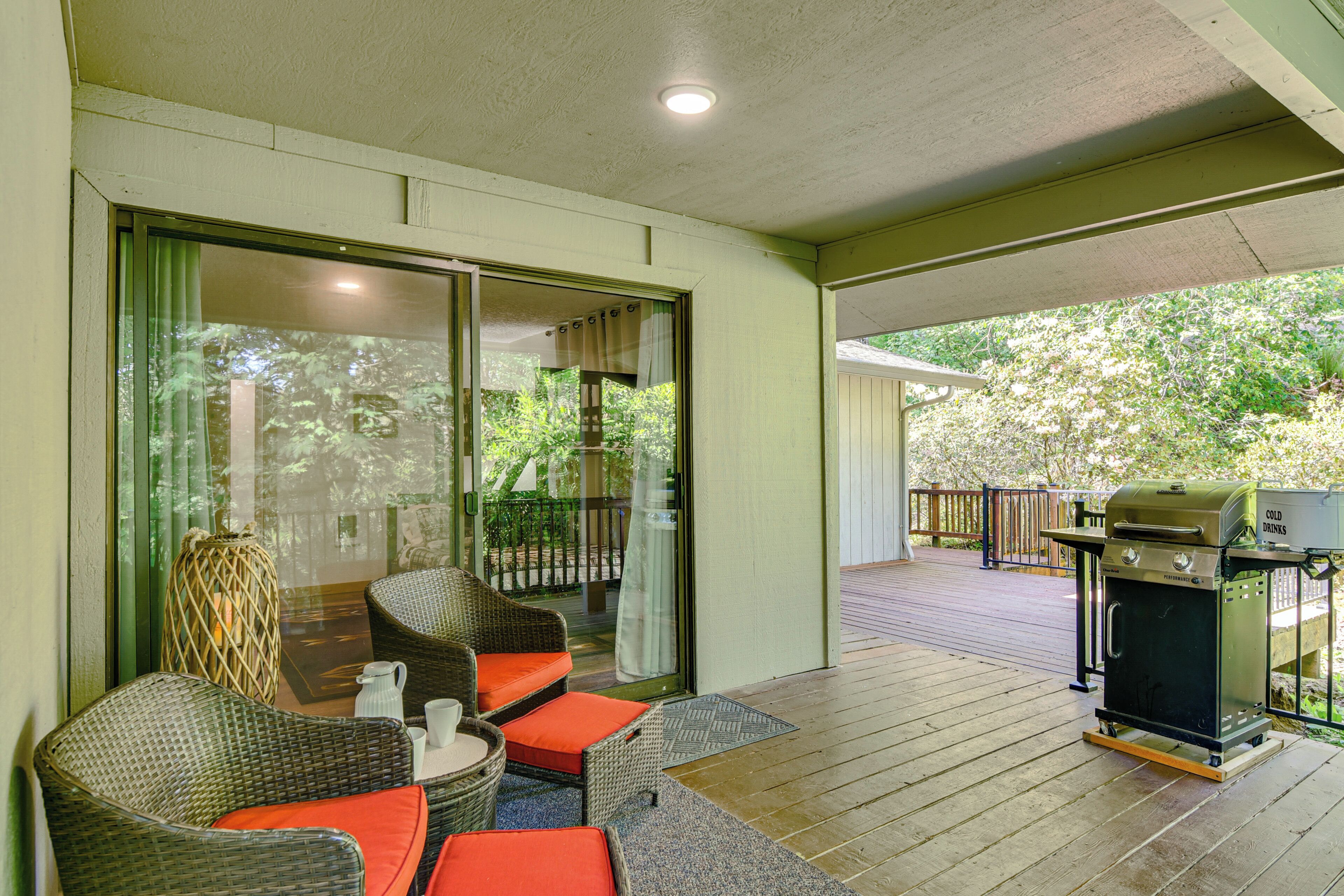 A covered outdoor area with wicker furniture, a grill, and a sliding glass door leading to a deck.